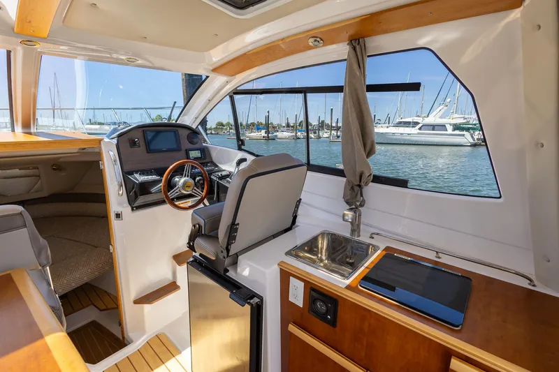 Slide: The Image of Interior of 2019 Cutwater C-24 Coupe boat with helm, sink, and marina view. - 6