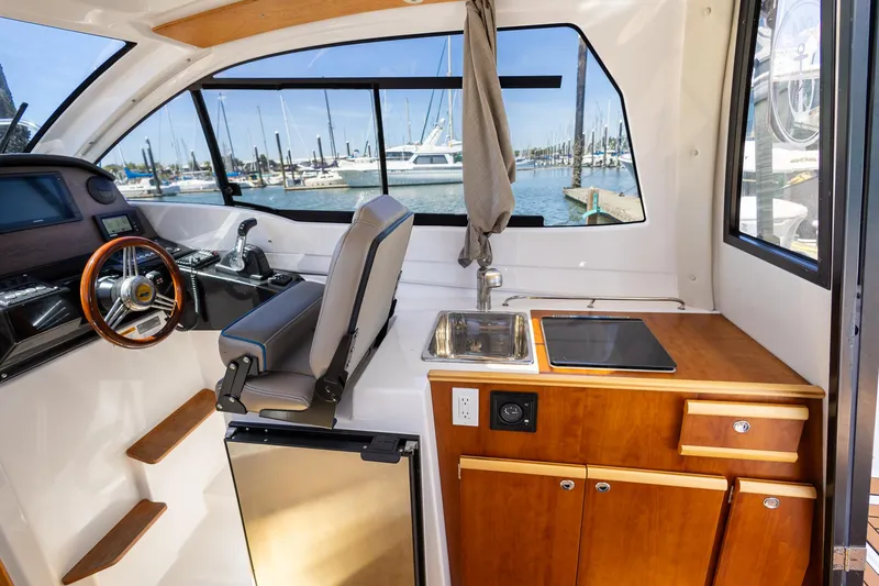 Slide: The Image of Interior of 2019 Cutwater C-24 Coupe boat with helm, kitchenette, and marina view. - 7