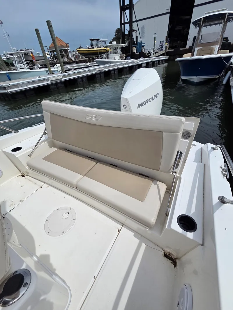 Slide: The Image of 2019 Boston Whaler 240 Dauntless boat with beige seating, docked at a marina. - 24