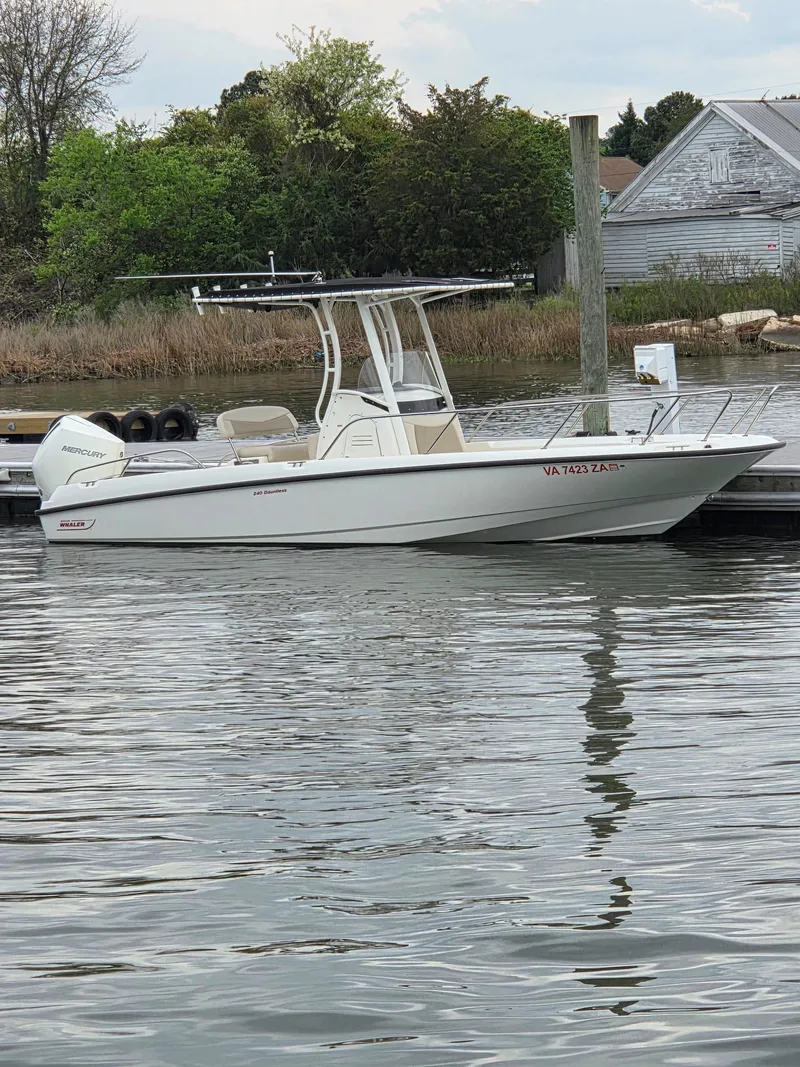 Slide: The Image of 2019 Boston Whaler 240 Dauntless boat docked by a calm waterfront. - 8