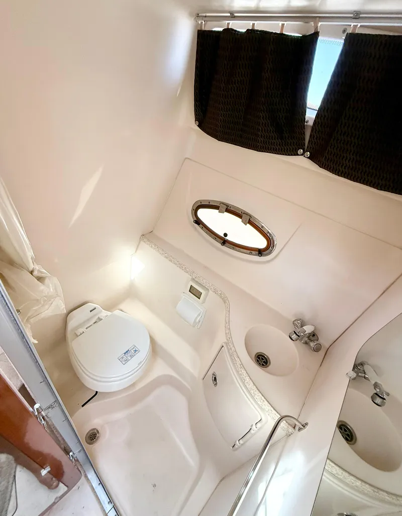 Slide: The Image of 2007 Regal 2860 Window Express boat bathroom with toilet, sink, and porthole window. - 19