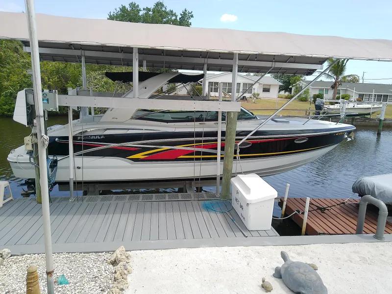 The Image of 2008 Formula 310 Sun Sport boat docked under a canopy on a sunny day. - 1