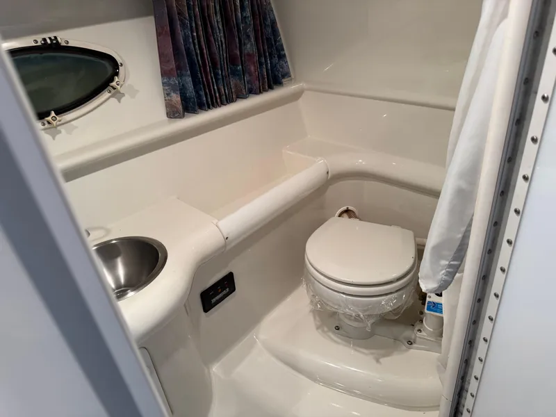 Slide: The Image of 1998 Formula 330 SS boat bathroom with sink, toilet, and porthole window. - 14