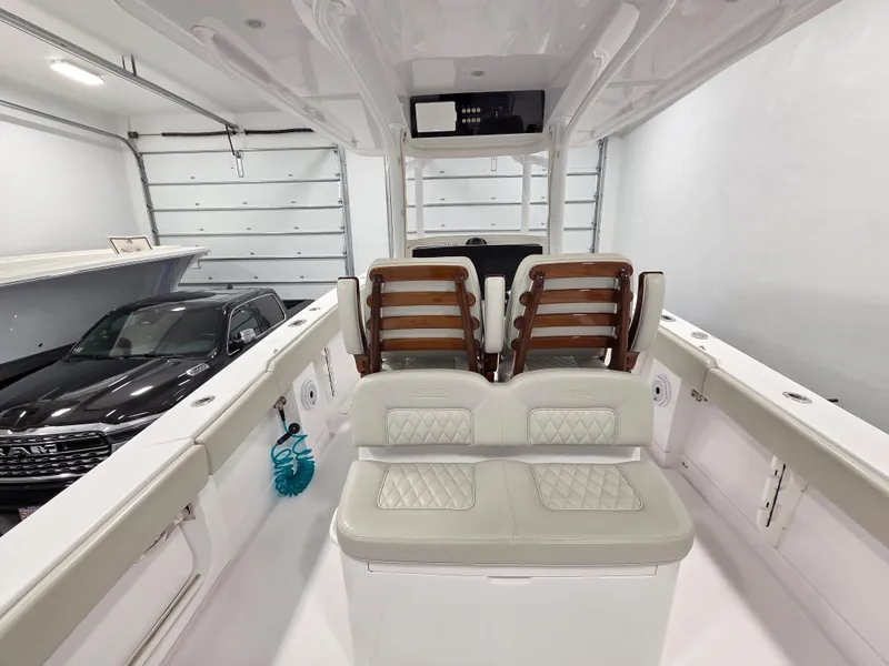 Slide: The Image of 2023 Jupiter 30 boat interior with cushioned seating in a garage setting. - 4