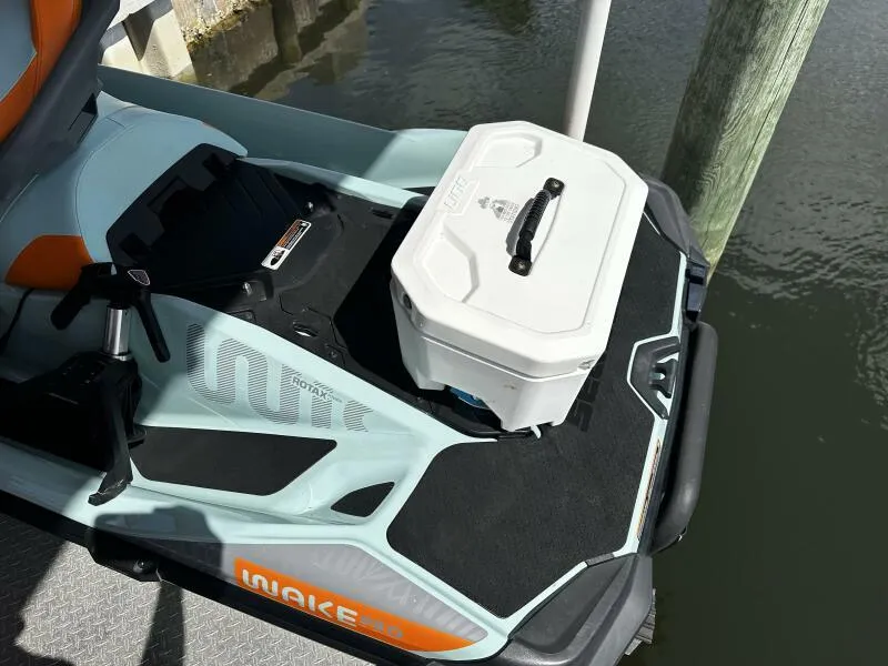 Slide: The Image of 2022 Sea-Doo Wake Pro 230 with storage box on deck, docked by water. - 10