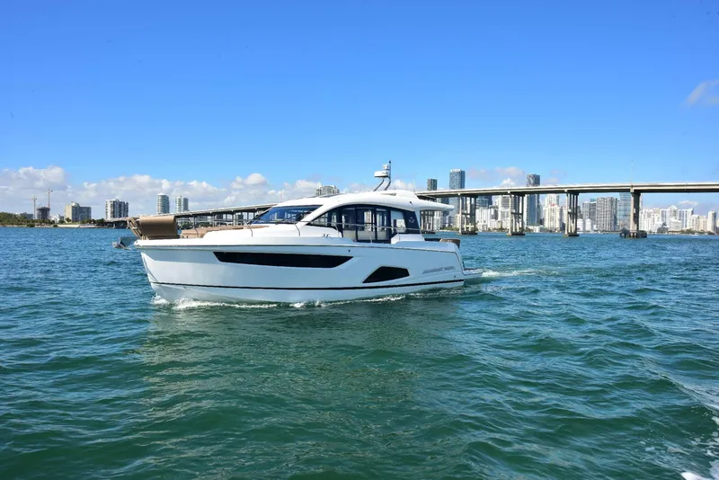 Slide: The Image of 2022 Sealine C430 #43 yacht cruising on open water with city skyline backdrop. - 24