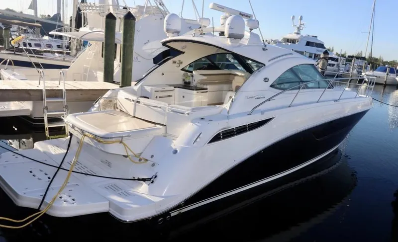 Slide: The Image of 2013 Sea Ray 410 Sundancer yacht docked at marina, sleek design, white exterior. - 2