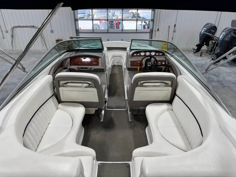 Slide: The Image of 2004 Cobalt 262 BR boat interior with white seating and dual consoles in a showroom. - 6