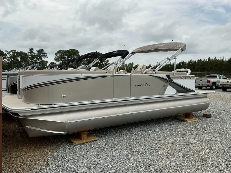 Slide: The Image of 2025 Avalon LSZ 23 Quad Lounger pontoon boat on gravel lot, overcast sky. - 1