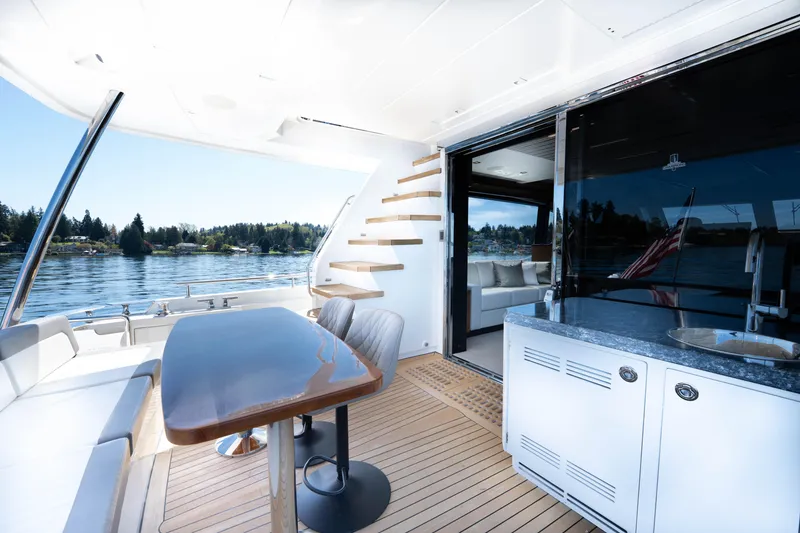 Slide: The Image of 2018 Ocean Alexander 70E Motoryacht deck with seating, table, and scenic water view. - 13