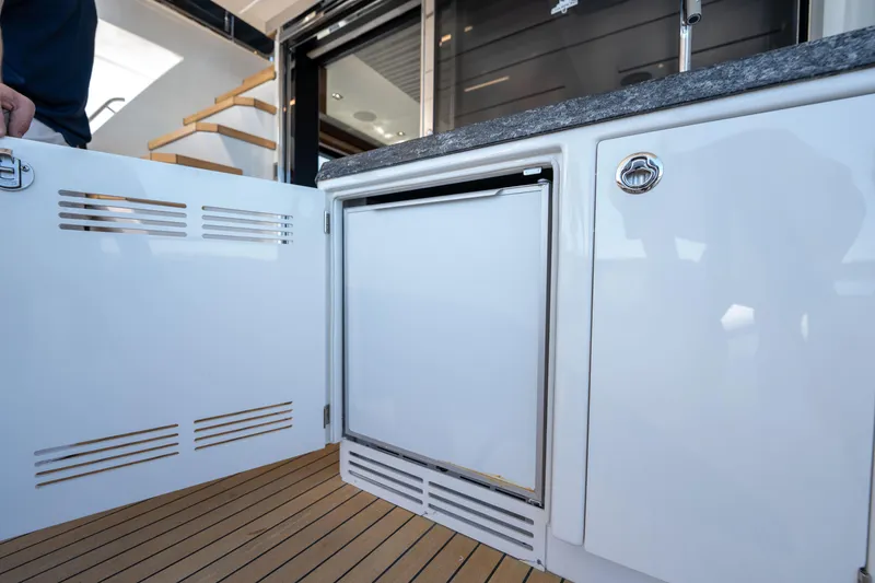 Slide: The Image of 2018 Ocean Alexander 70E Motoryacht interior with open cabinet and compact refrigerator. - 14