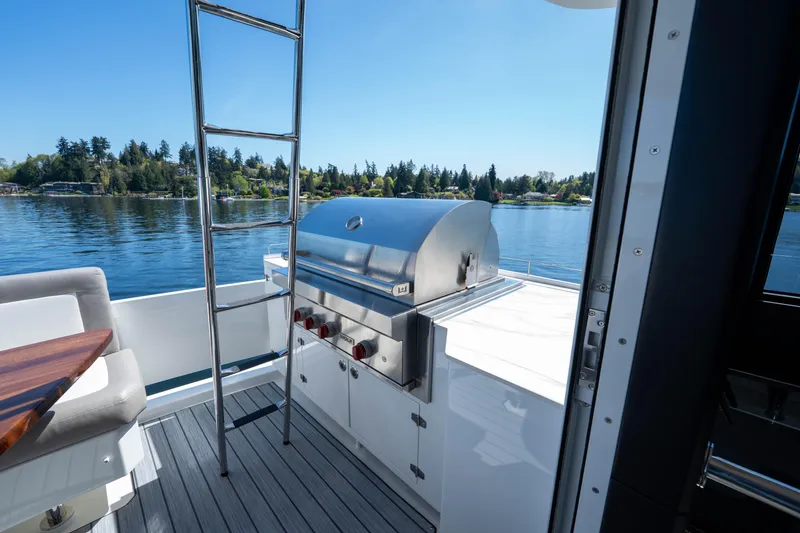 Slide: The Image of Outdoor grill on 2018 Ocean Alexander 70E Motoryacht deck, overlooking serene water and trees. - 51