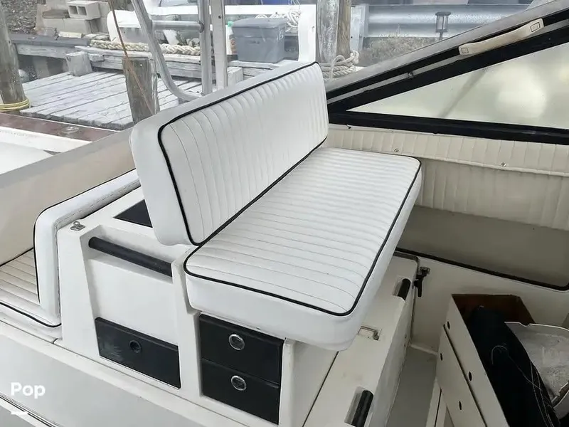 Slide: The Image of 1988 Black Watch 30 Sportfish Convertible interior with white cushioned seating and storage drawers. - 8
