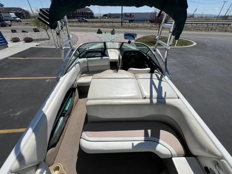 Slide: The Image of 2003 Malibu 23 XTi boat interior with seating and steering wheel, parked outdoors. - 10
