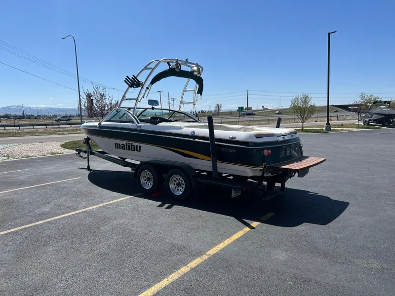 Slide: The Image of 2003 Malibu 23 XTi boat on trailer in parking lot under clear blue sky. - 7