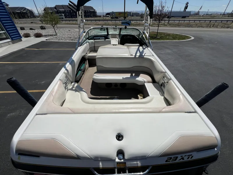 Slide: The Image of 2003 Malibu 23 XTi boat with spacious seating, parked in a lot under clear skies. - 9