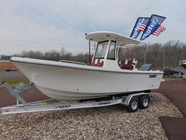 The Image of 2025 Parker 2400 Center Console boat on trailer with flags, parked outdoors. - 1
