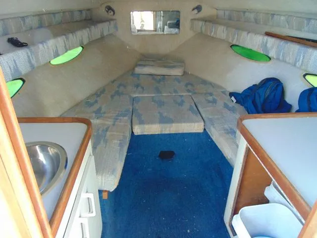 Slide: The Image of 1990 Sea Ray 260 Overnighter cabin interior with seating, sink, and storage. - 14