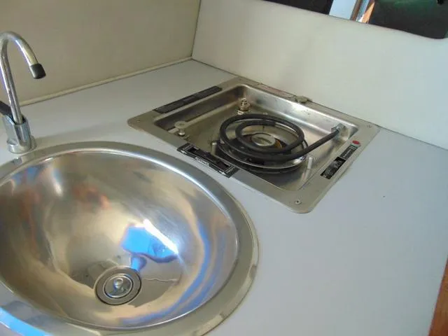 Slide: The Image of Compact kitchen area in a 1990 Sea Ray 260 Overnighter boat, featuring a sink and stove. - 17