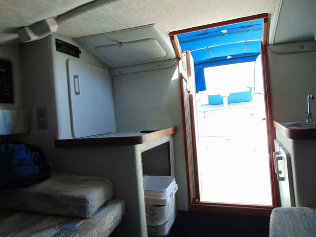 Slide: The Image of Interior of 1990 Sea Ray 260 Overnighter boat, featuring seating and compact kitchenette. - 23