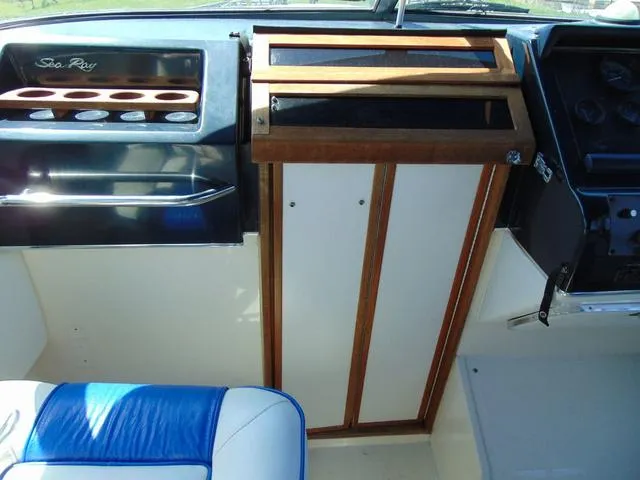 Slide: The Image of 1990 Sea Ray 260 Overnighter cockpit with blue seating and wooden paneling. - 27