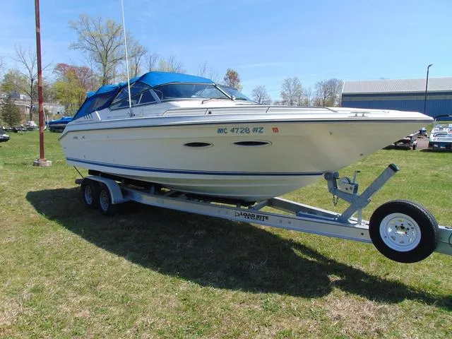 Slide: The Image of 1990 Sea Ray 260 Overnighter boat on trailer, parked on grass with blue canopy. - 4