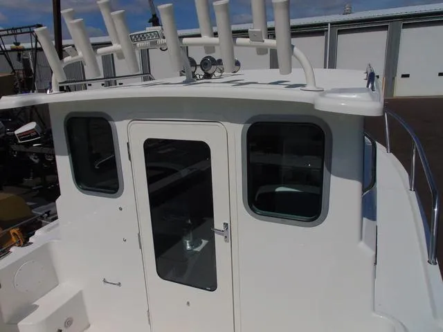 Slide: The Image of 2025 Parker 2420 Sport Cabin boat with rod holders and cabin door. - 12