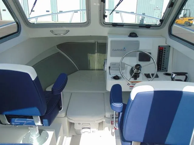 Slide: The Image of 2025 Parker 2420 Sport Cabin interior with blue seating and Garmin navigation system. - 16