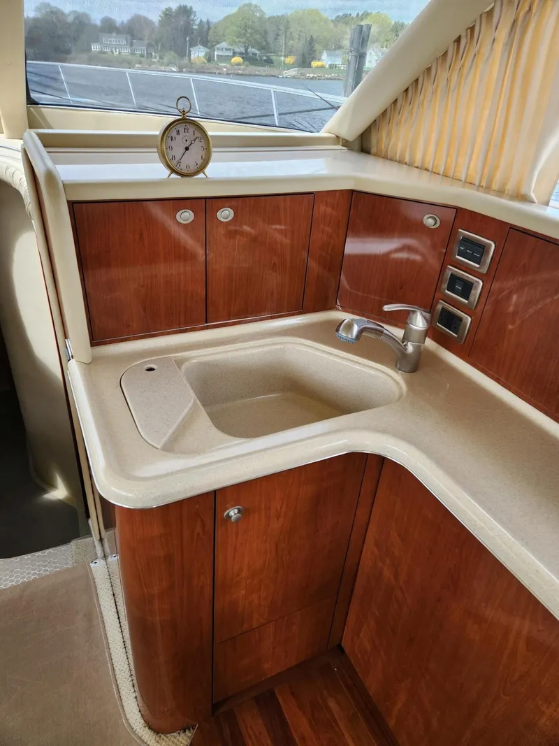 Slide: The Image of 2004 Sea Ray 480 Sedan Bridge kitchen with wood cabinetry and sink. - 24