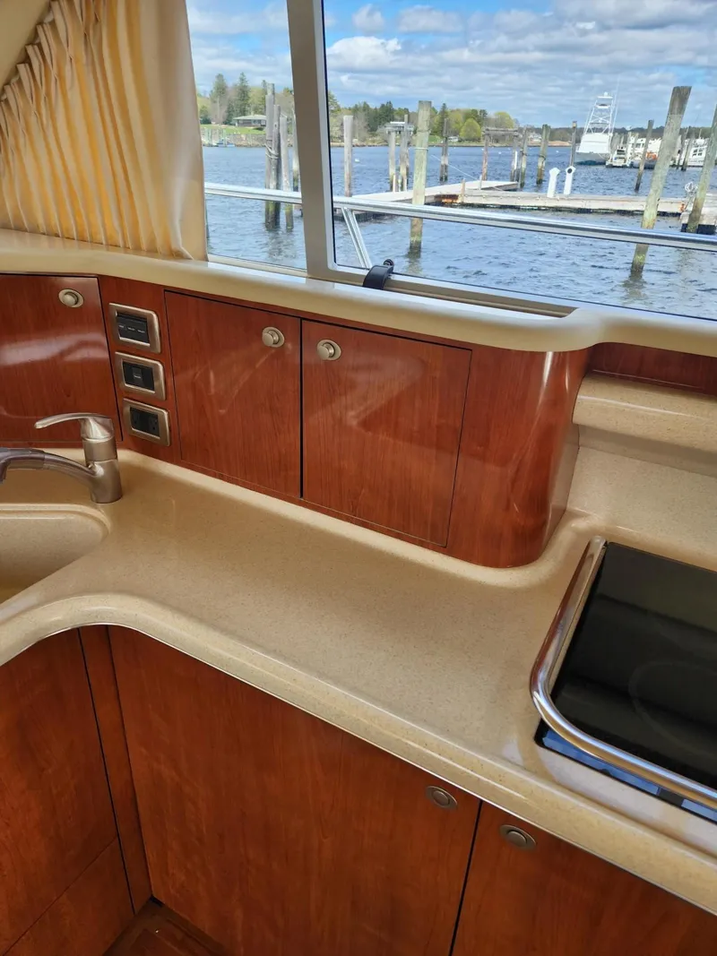 Slide: The Image of 2004 Sea Ray 480 Sedan Bridge kitchen with wood cabinets and water view. - 26