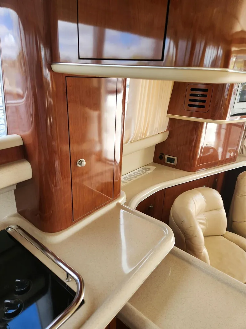 Slide: The Image of 2004 Sea Ray 480 Sedan Bridge interior with polished wood and beige leather seating. - 28