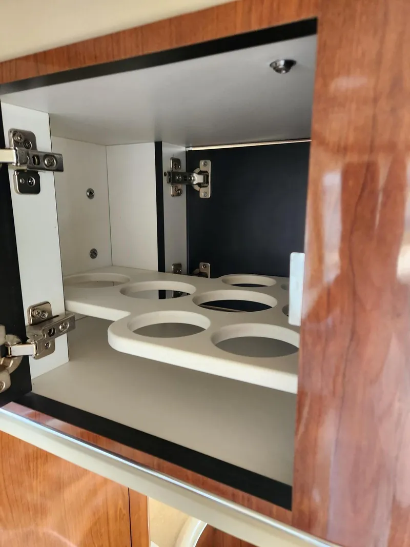 Slide: The Image of 2004 Sea Ray 480 Sedan Bridge cabinet with cup holders and wooden finish. - 29