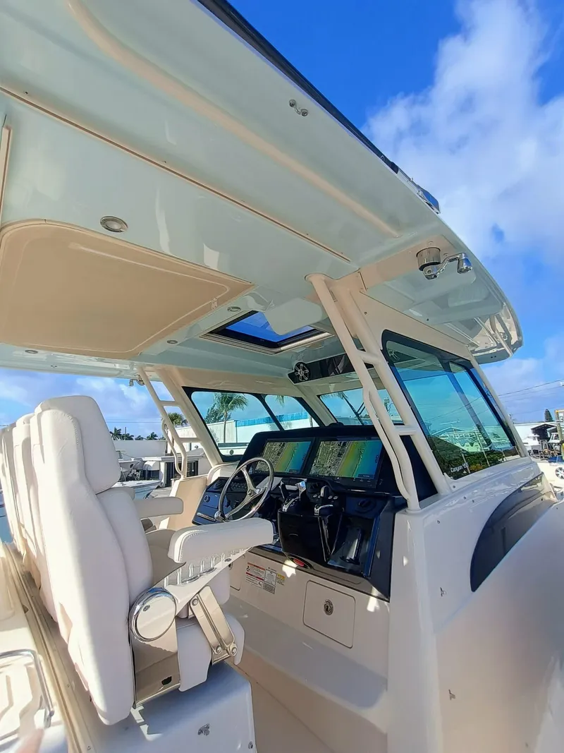 Slide: The Image of 2025 Grady-White Canyon 456 boat interior with modern helm and seating under clear blue sky. - 10