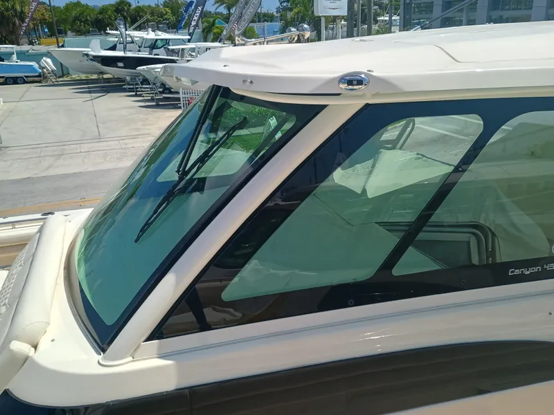 Slide: The Image of 2025 Grady-White Canyon 456 boat windshield and cabin detail in marina setting. - 40