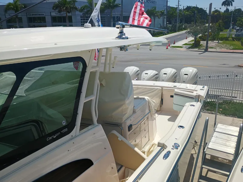 Slide: The Image of 2025 Grady-White Canyon 456 boat with multiple engines, docked near a dealership. - 41