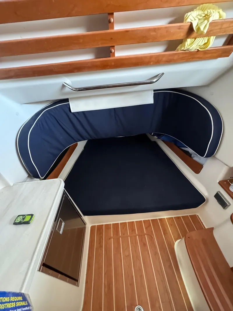 Slide: The Image of 2023 Grady-White Canyon 376 cabin interior with wooden flooring and blue cushioned seating. - 14