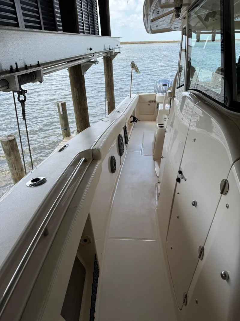 Slide: The Image of 2023 Grady-White Canyon 376 boat interior, docked by the water, showcasing sleek design. - 21