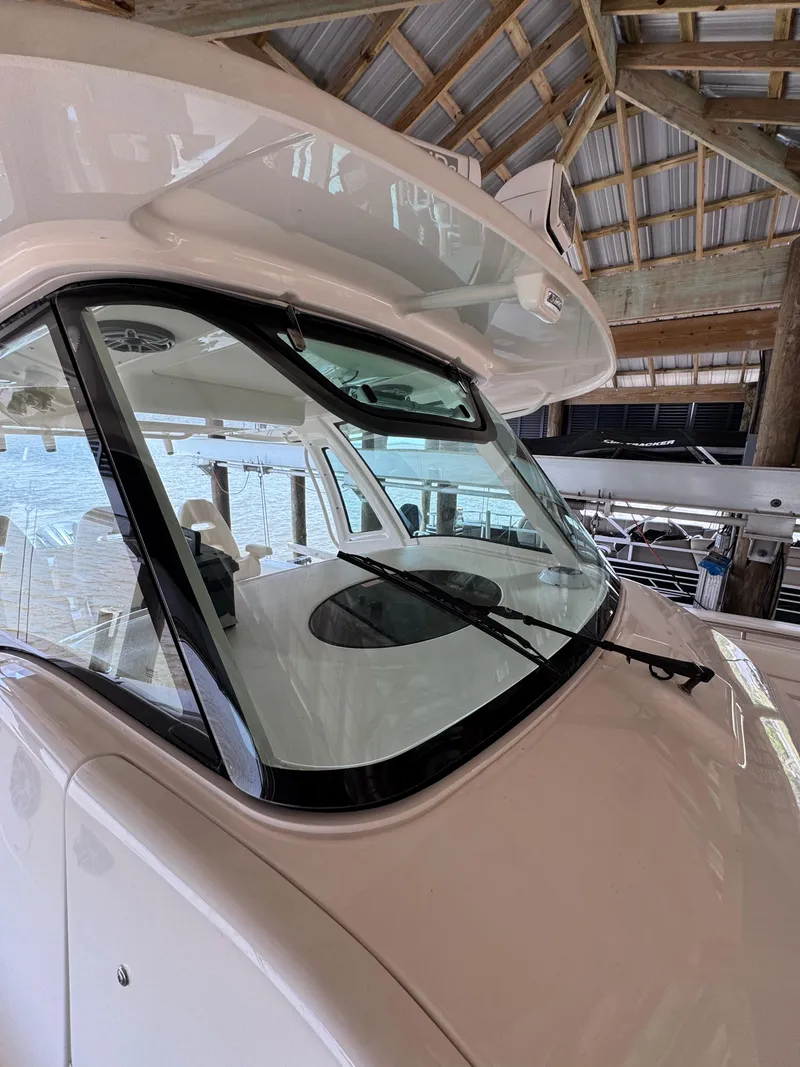 Slide: The Image of 2023 Grady-White Canyon 376 boat under a wooden dock, showcasing windshield and cabin. - 9