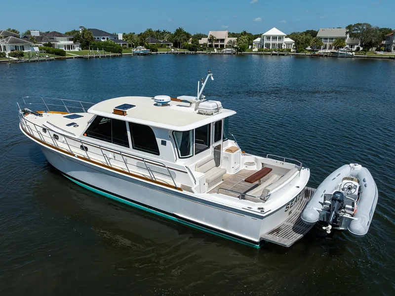 Slide: The Image of 2014 Grand Banks 46 Eastbay SX yacht on a serene lake with nearby houses. - 17