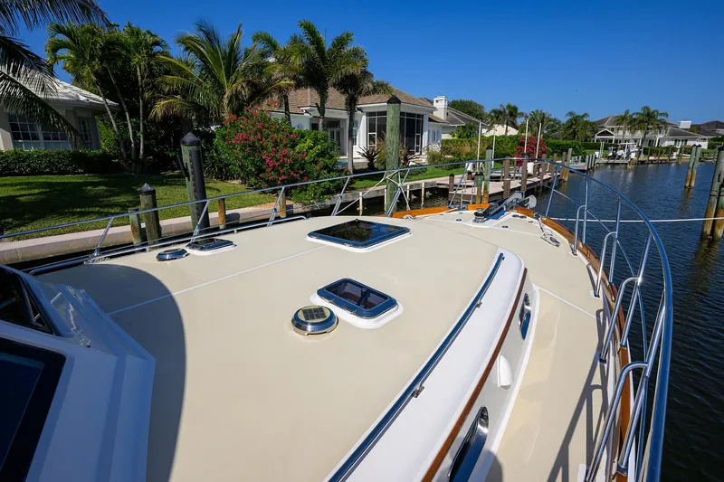 Slide: The Image of 2014 Grand Banks 46 Eastbay SX yacht docked by waterfront homes, surrounded by lush greenery. - 26