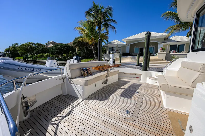 Slide: The Image of 2014 Grand Banks 46 Eastbay SX yacht deck with seating, docked near a waterfront home. - 28