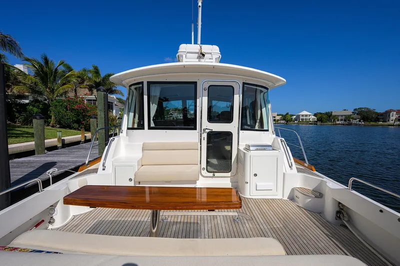 Slide: The Image of 2014 Grand Banks 46 Eastbay SX yacht with spacious deck and seating, docked by waterfront homes. - 30