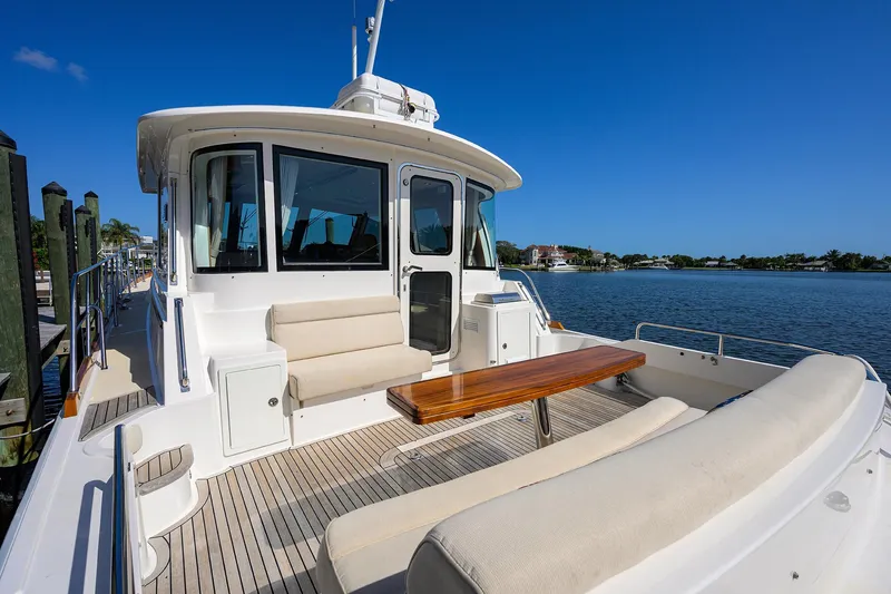 Slide: The Image of 2014 Grand Banks 46 Eastbay SX yacht with spacious deck and seating, docked by serene waters. - 31