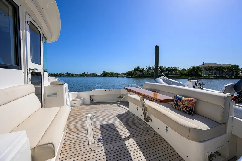 Slide: The Image of 2014 Grand Banks 46 Eastbay SX yacht deck with seating, table, and scenic water view. - 32