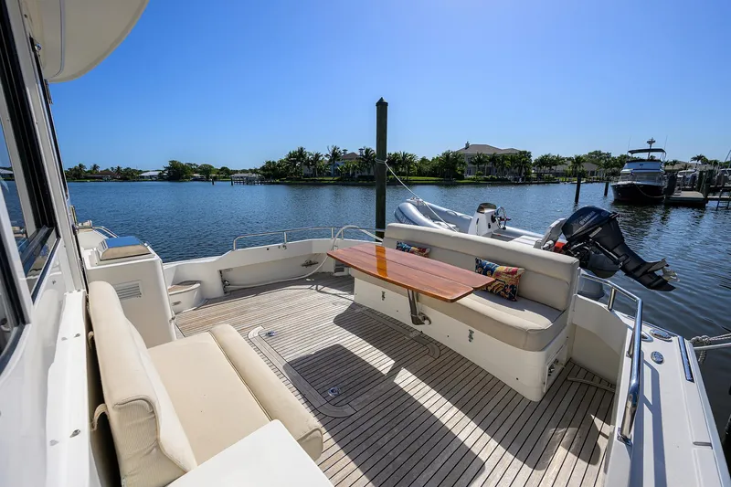 Slide: The Image of 2014 Grand Banks 46 Eastbay SX yacht deck with seating and table, overlooking serene water. - 36