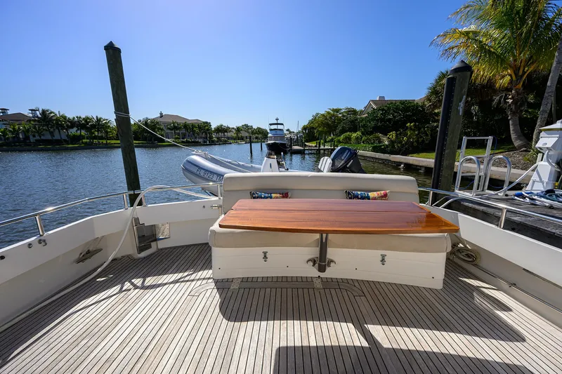 Slide: The Image of 2014 Grand Banks 46 Eastbay SX yacht deck with wooden table, docked by a scenic waterfront. - 37