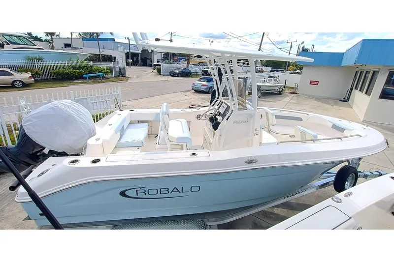 Slide: The Image of 2025 Robalo R202 Explorer boat in a showroom, side view, white and blue design. - 3