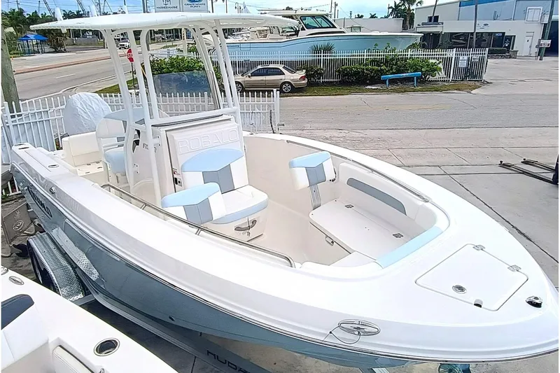 Slide: The Image of 2025 Robalo R202 Explorer boat on trailer, white and blue design, parked outdoors. - 6