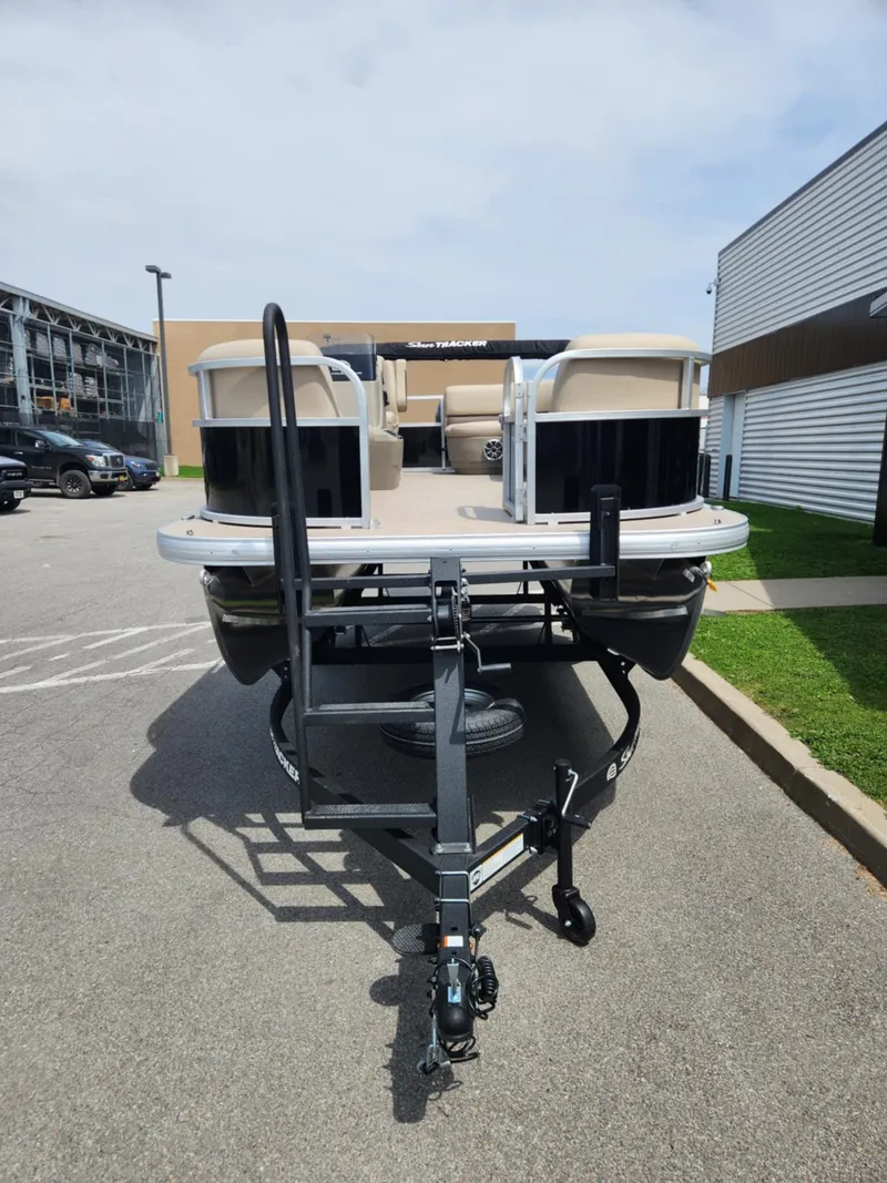 Slide: The Image of 2025 Sun Tracker Party Barge 16 DLX pontoon boat on trailer in parking lot. - 2