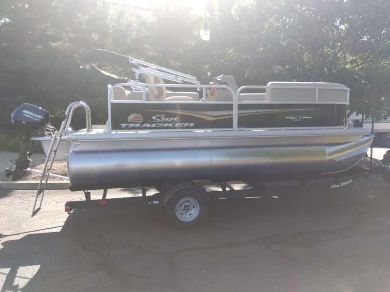 The Image of 2025 Sun Tracker Party Barge 16 DLX pontoon boat on trailer, parked outdoors. - 0